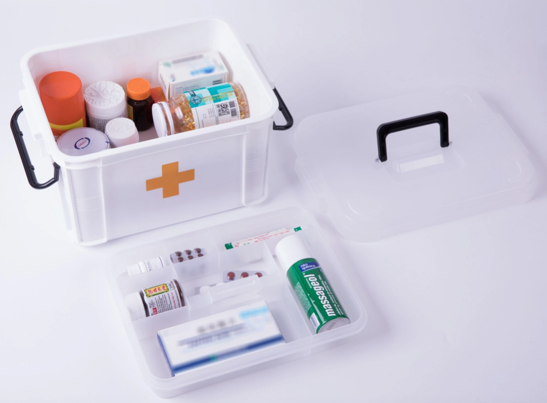 Portable white First Aid | Injection Supplies Storage Box with an assortment of medical supplies and medications, including sterile glass vials and syringes, open lid beside it by Faire.com.