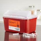 A red, puncture-resistant MedPlus Sharps Container - 1 Gallon (4 quart) with a secure lid, labeled for infectious waste, sits on a surface next to discarded syringes and needles. This OSHA-compliant container ensures safe and proper disposal of hazardous materials.