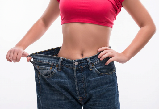 A woman is holding up her Custom Item jeans on a white background, showcasing her successful Custom Item weight loss regimen.